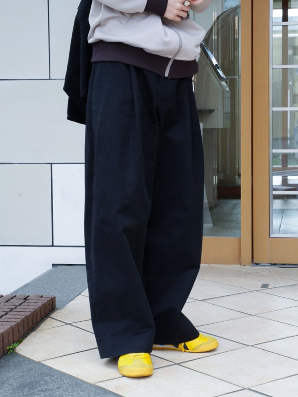 ベージュ系のジャージ、ブラック系のショルダーバッグ、ブラック系のチノパンツを着用したメンズの春コーディネートの5枚目の写真