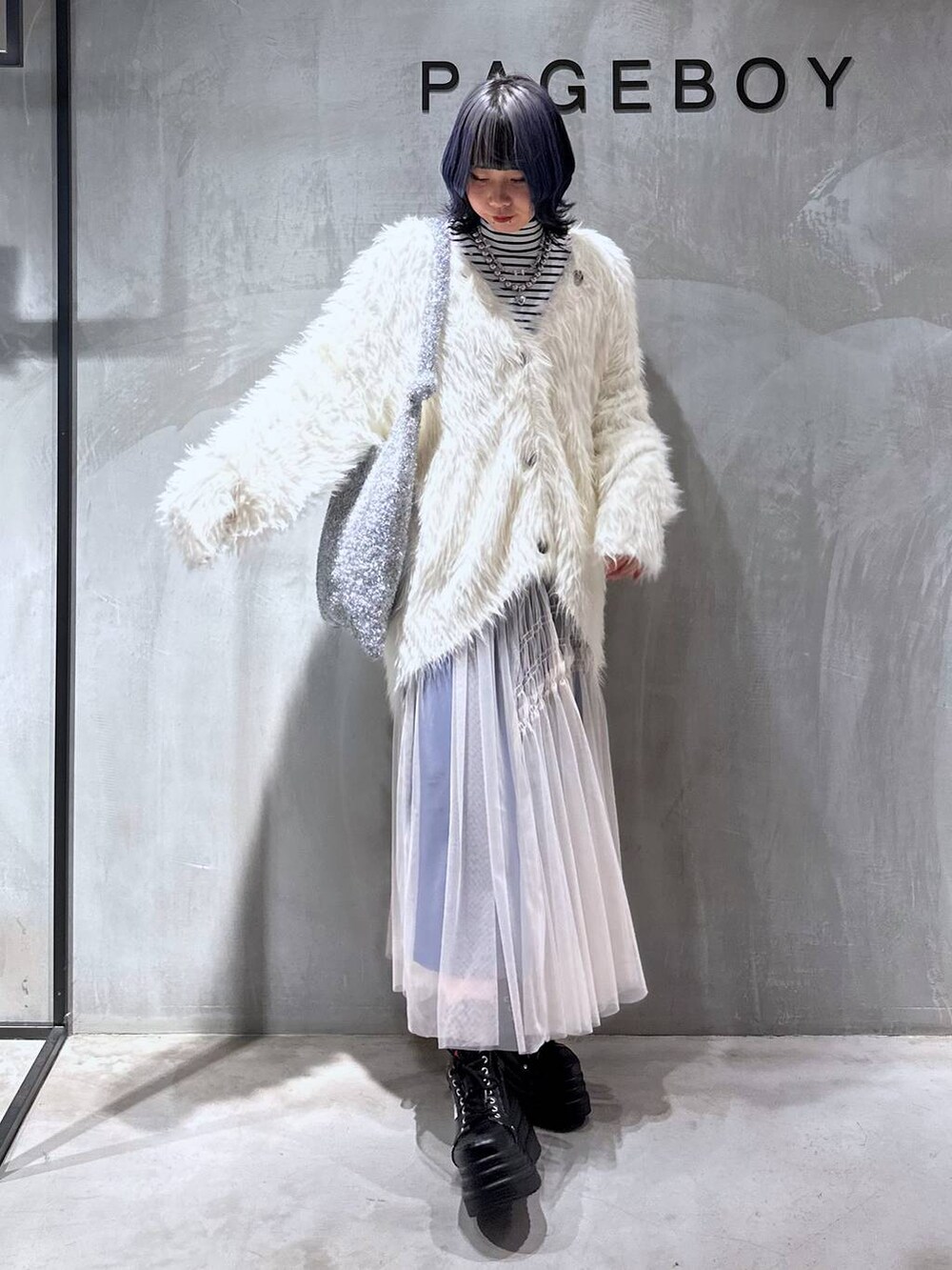 シルバー系のトートバッグ、ホワイト系のカーディガン/ボレロ、ホワイト系のスカートを着用したレディースの秋コーディネートの3枚目の写真