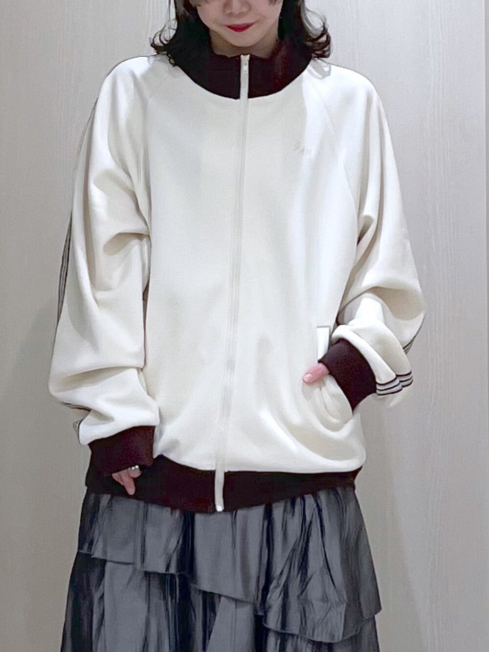 ホワイト系のブルゾン、グレー系のスカート、ブルー系のスニーカーを着用したレディースの春コーディネートの2枚目の写真