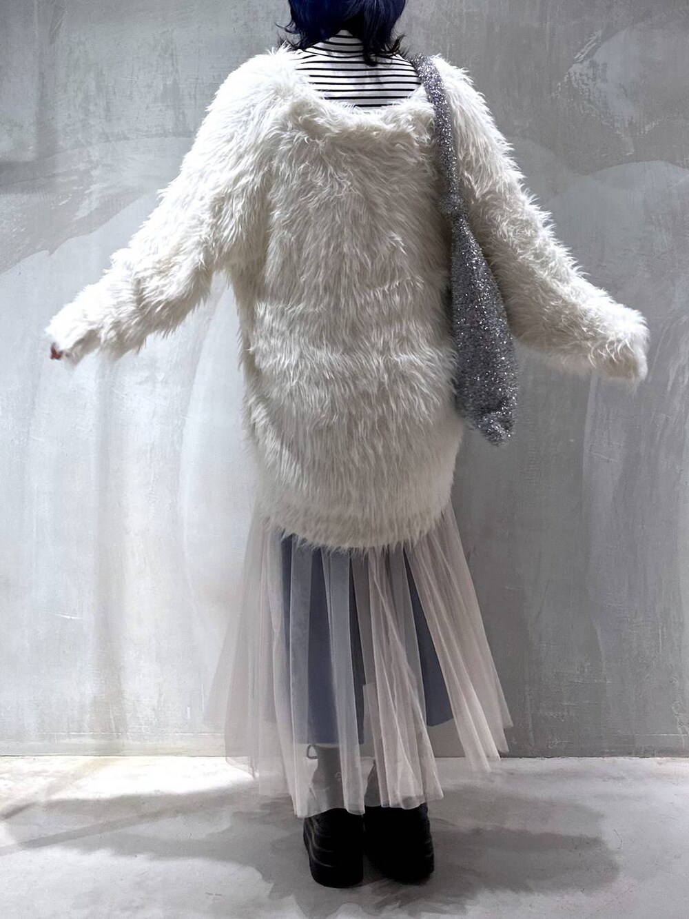 シルバー系のトートバッグ、ホワイト系のカーディガン/ボレロ、ホワイト系のスカートを着用したレディースの秋コーディネートの6枚目の写真