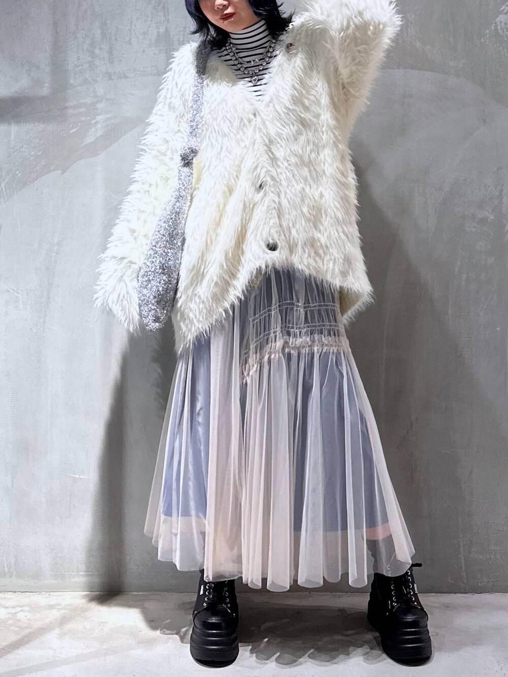 シルバー系のトートバッグ、ホワイト系のカーディガン/ボレロ、ホワイト系のスカートを着用したレディースの秋コーディネートの4枚目の写真