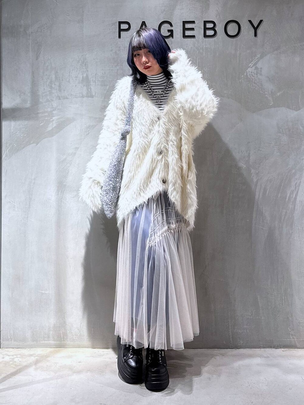 シルバー系のトートバッグ、ホワイト系のカーディガン/ボレロ、ホワイト系のスカートを着用したレディースの秋コーディネートの2枚目の写真