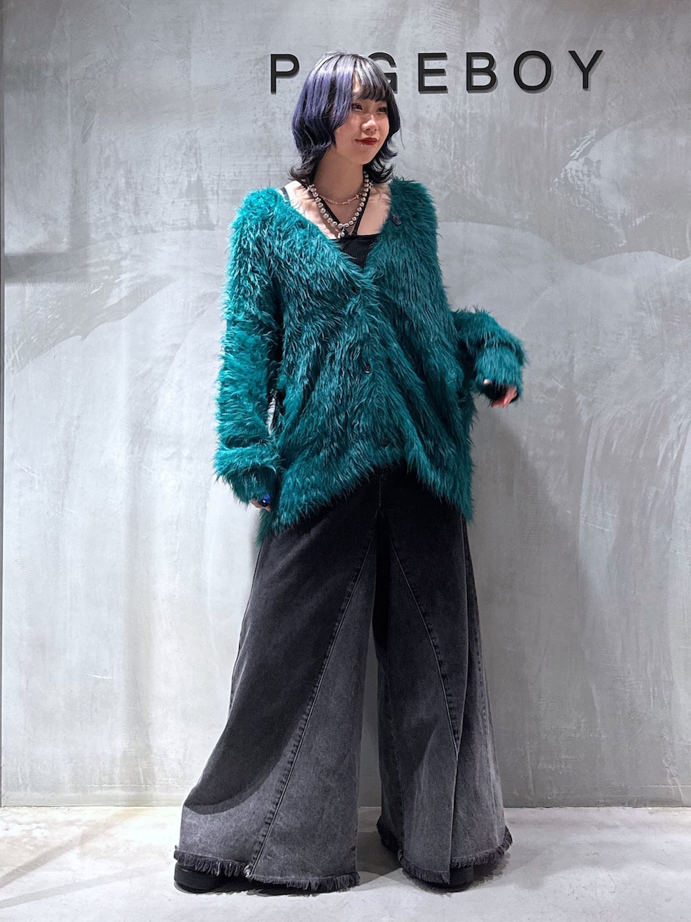 ブラック系のキャミソール、グリーン系のカーディガン/ボレロ、ブラック系のデニムパンツを着用したレディースの秋コーディネートの2枚目の写真