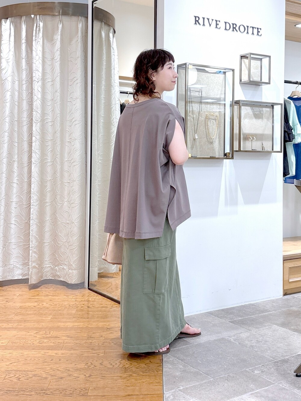 グレー系のTシャツ/カットソー、グリーン系のスカート、ブラウン系のハンドバッグを着用したレディースの夏コーディネートの3枚目の写真