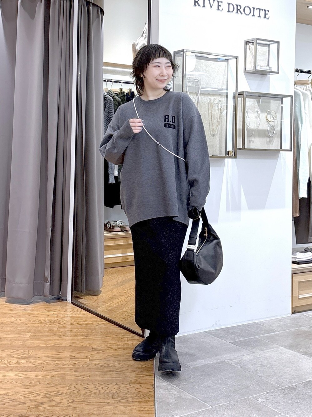 グレー系のニット/セーター、ブラック系のその他アウター、ブラック系のスカートを着用したレディースの秋コーディネートの2枚目の写真
