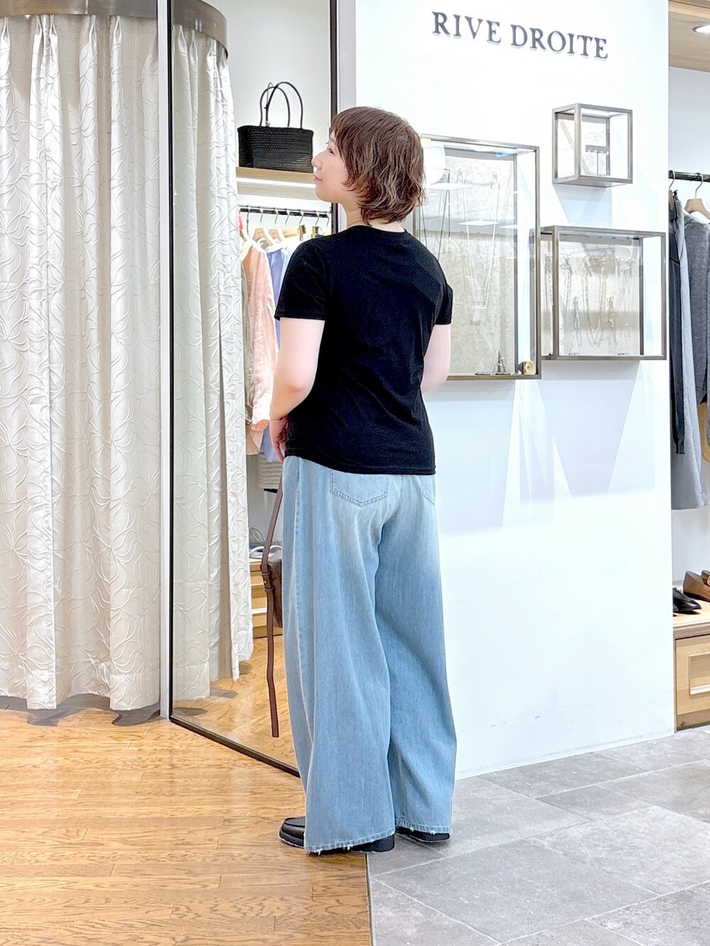 ブラック系のTシャツ/カットソー、ブラウン系のショルダーバッグ、ブルー系のデニムパンツを着用したレディースの夏コーディネートの4枚目の写真