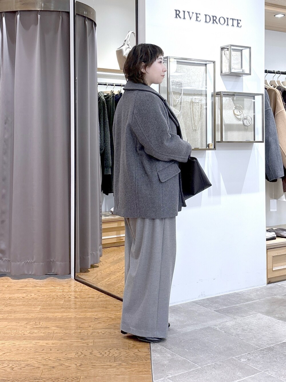 グレー系のTシャツ/カットソー、グレー系のピーコート、ブラック系のハンドバッグを着用したレディースの秋コーディネートの3枚目の写真