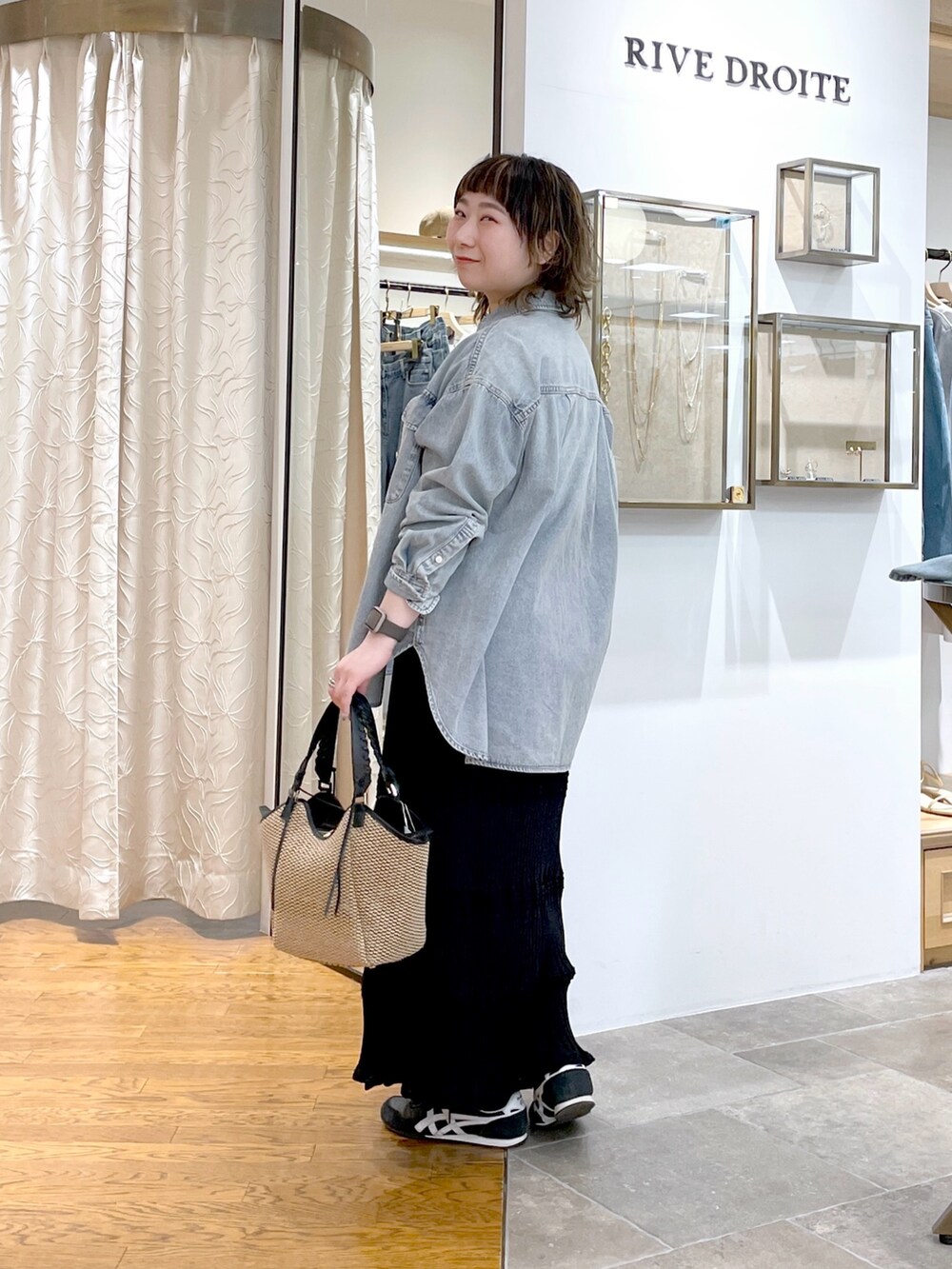 ブルー系のシャツ/ブラウス、ブラック系のニット/セーター、ブラック系のスカートを着用したレディースの春コーディネートの2枚目の写真