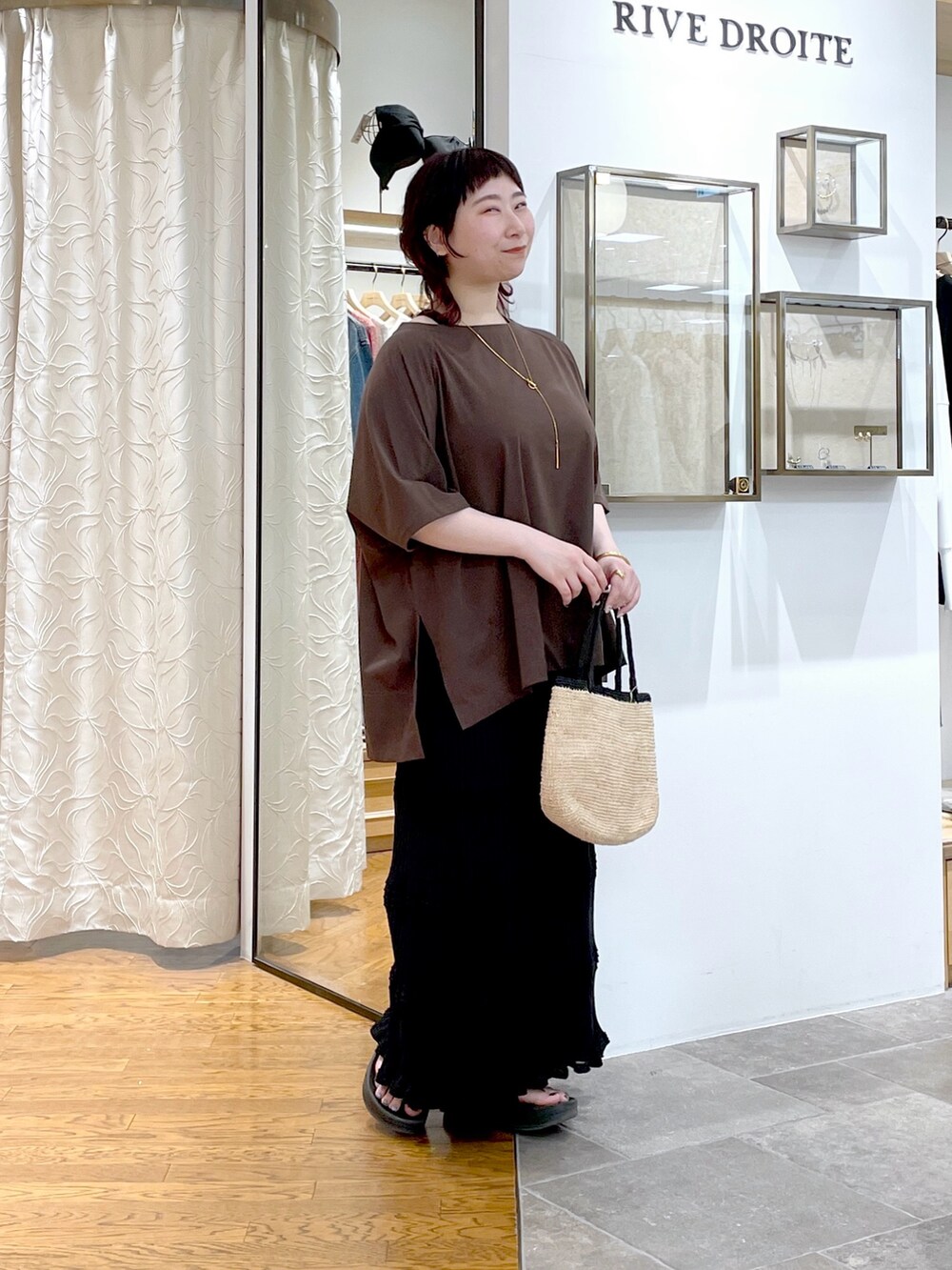 ブラウン系のTシャツ/カットソー、ブラック系のスカート、ゴールド系のネックレスを着用したレディースの春コーディネートの2枚目の写真