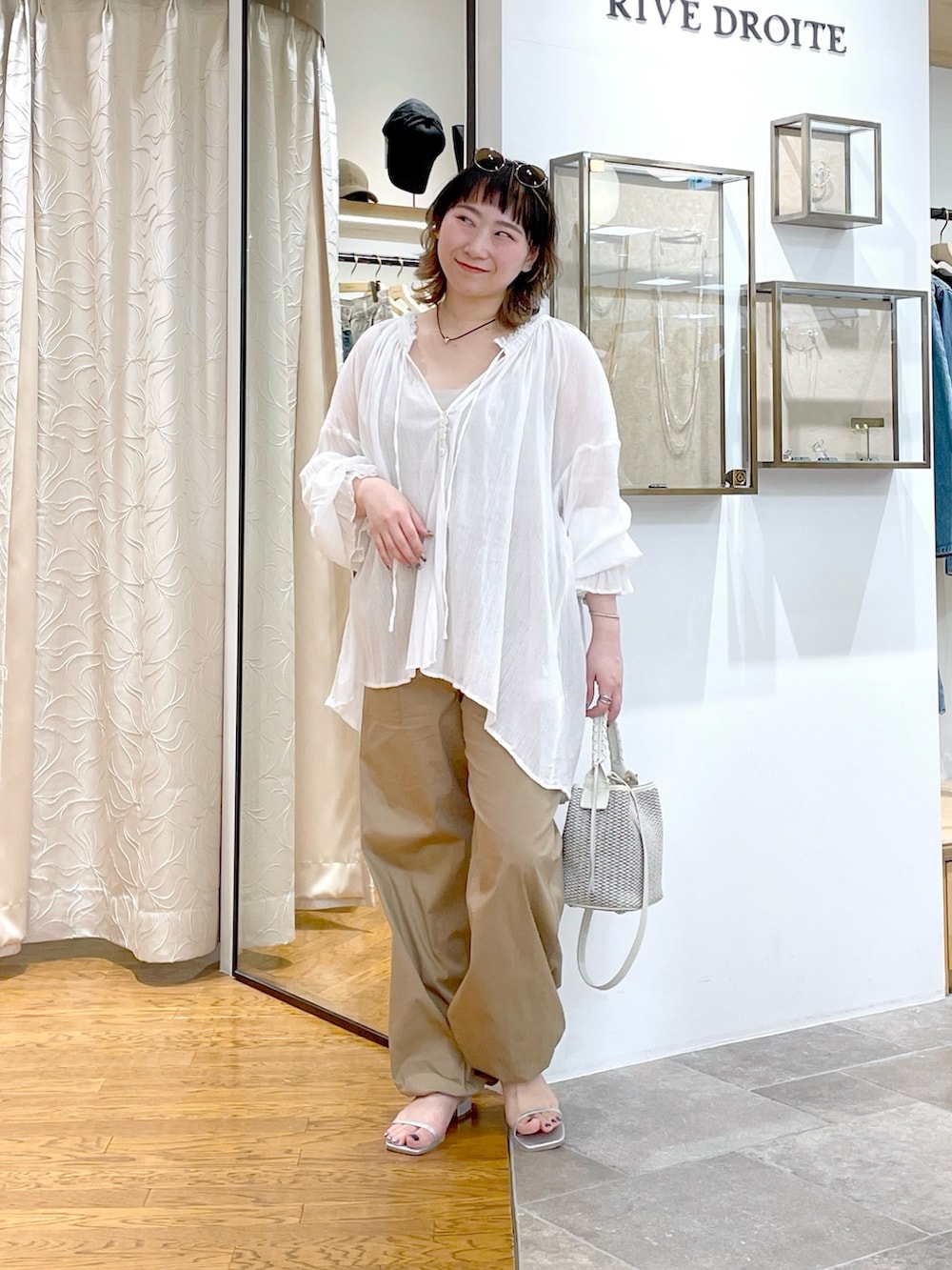 ベージュ系のタンクトップ、ホワイト系のシャツ/ブラウス、ホワイト系のハンドバッグを着用したレディースの春コーディネートの4枚目の写真