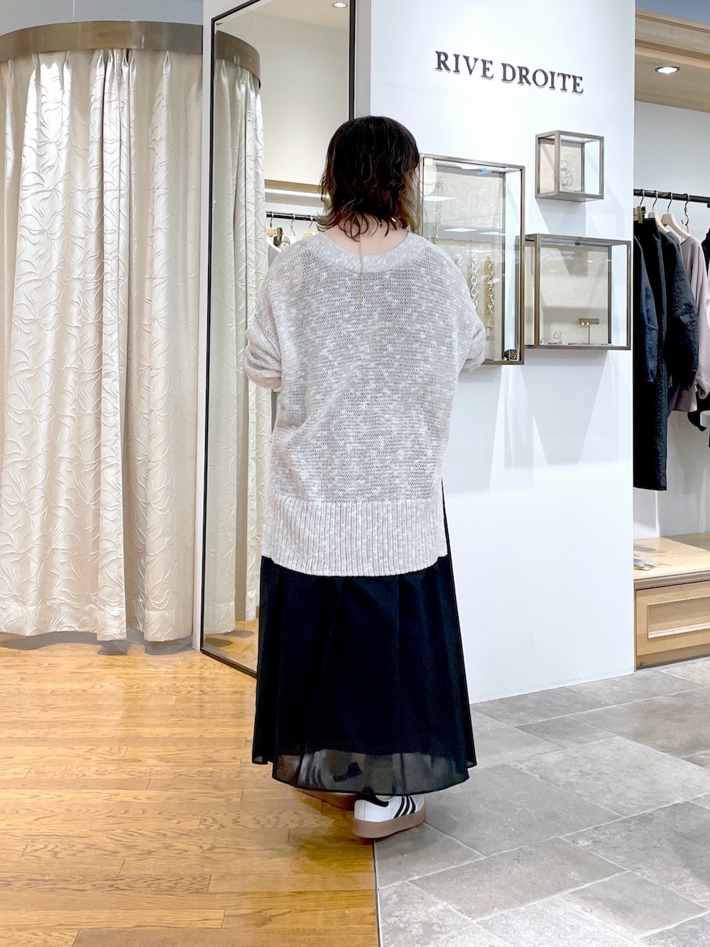 ブラック系のスカート、ホワイト系のボストンバッグ、グレー系のカーディガン/ボレロを着用したレディースの春コーディネートの3枚目の写真