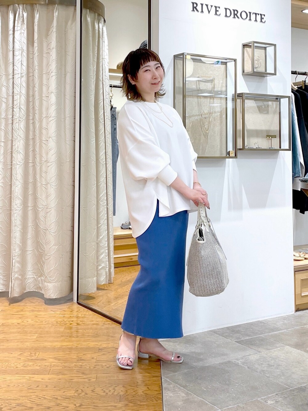 ホワイト系のTシャツ/カットソー、ブルー系のスカート、ホワイト系のトートバッグを着用したレディースの春コーディネートの2枚目の写真