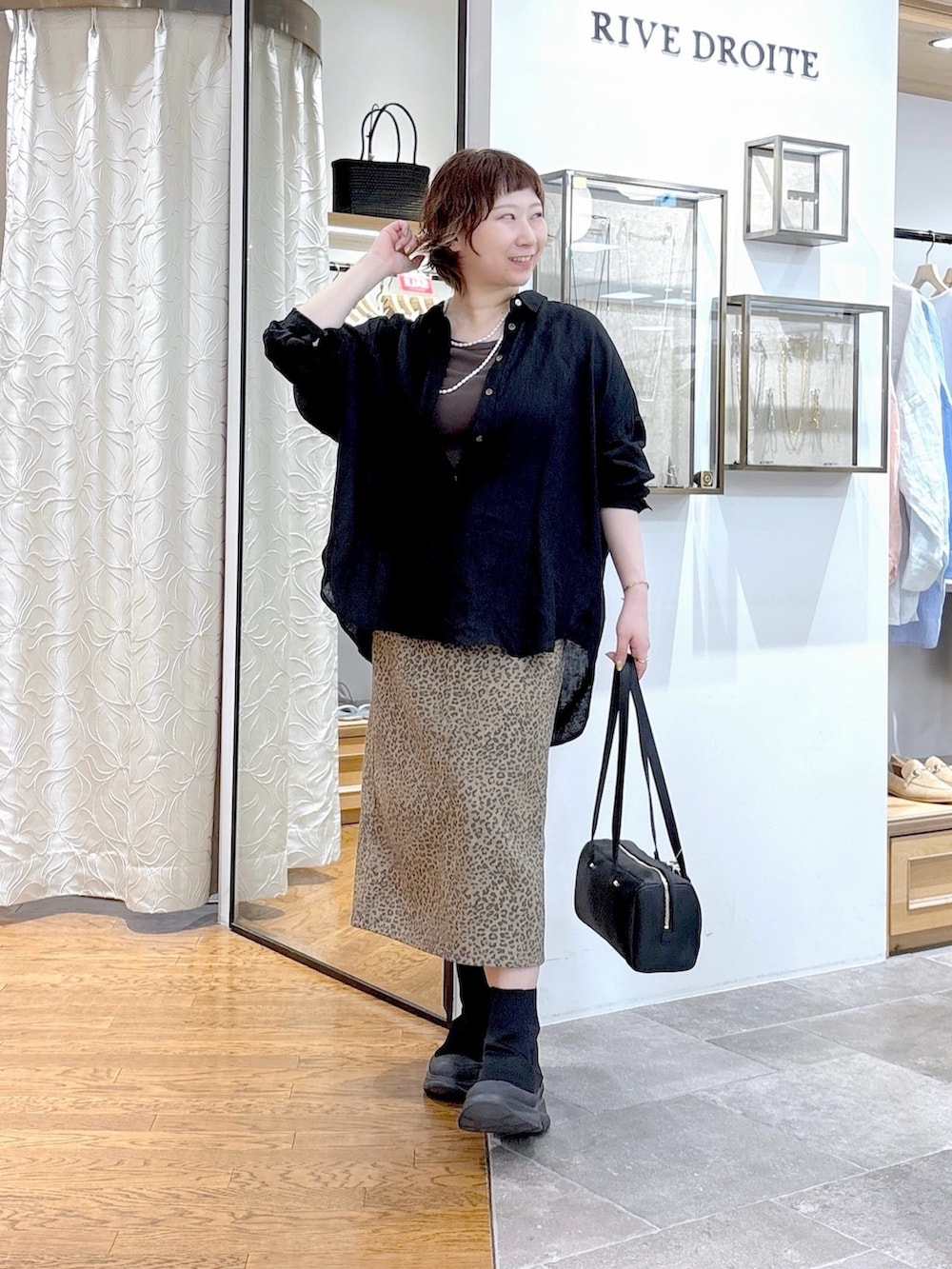 ブラック系のシャツ/ブラウス、ブラウン系のスカート、ブラック系のショルダーバッグを着用したレディースの夏コーディネートの4枚目の写真