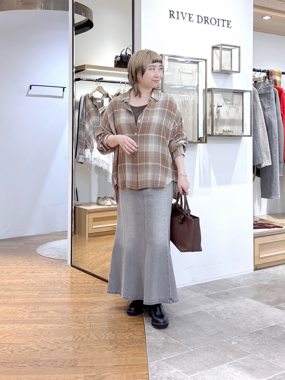 ブラウン系のニット/セーター、ベージュ系のシャツ/ブラウス、グレー系のデニムスカートを着用したレディースの秋コーディネートの4枚目の写真
