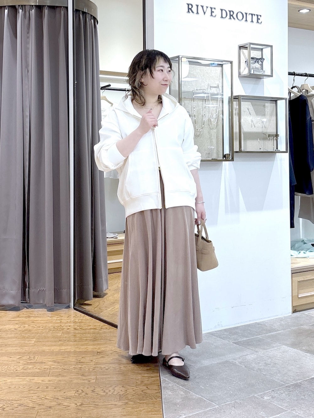 ホワイト系のパーカー、ブルー系のテーラードジャケット、ブラウン系のスカートを着用したレディースの春コーディネートの2枚目の写真