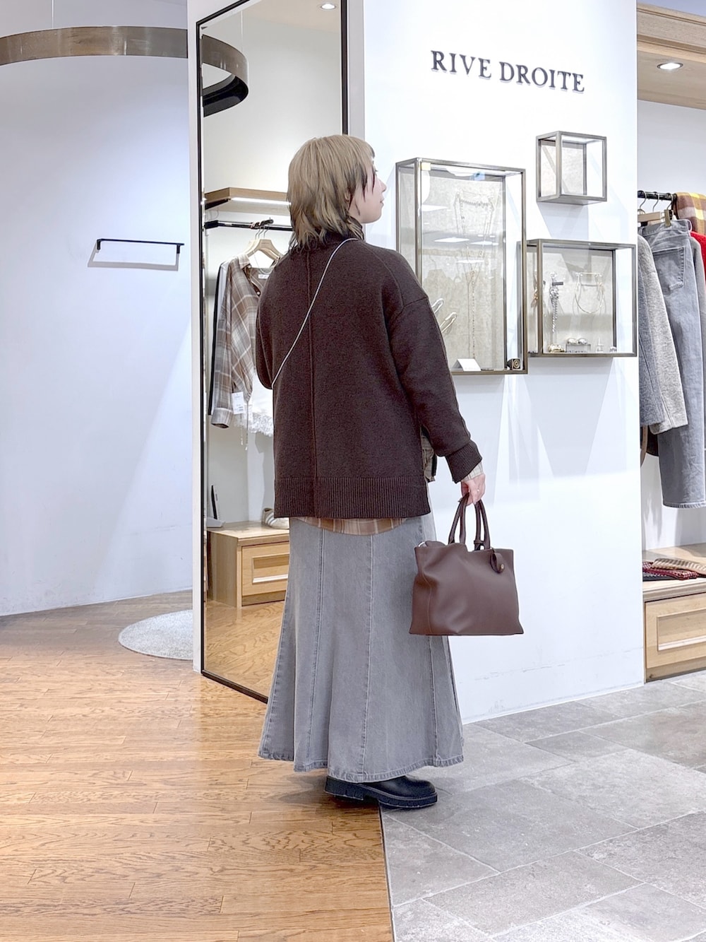 ブラウン系のニット/セーター、ベージュ系のシャツ/ブラウス、グレー系のデニムスカートを着用したレディースの秋コーディネートの3枚目の写真