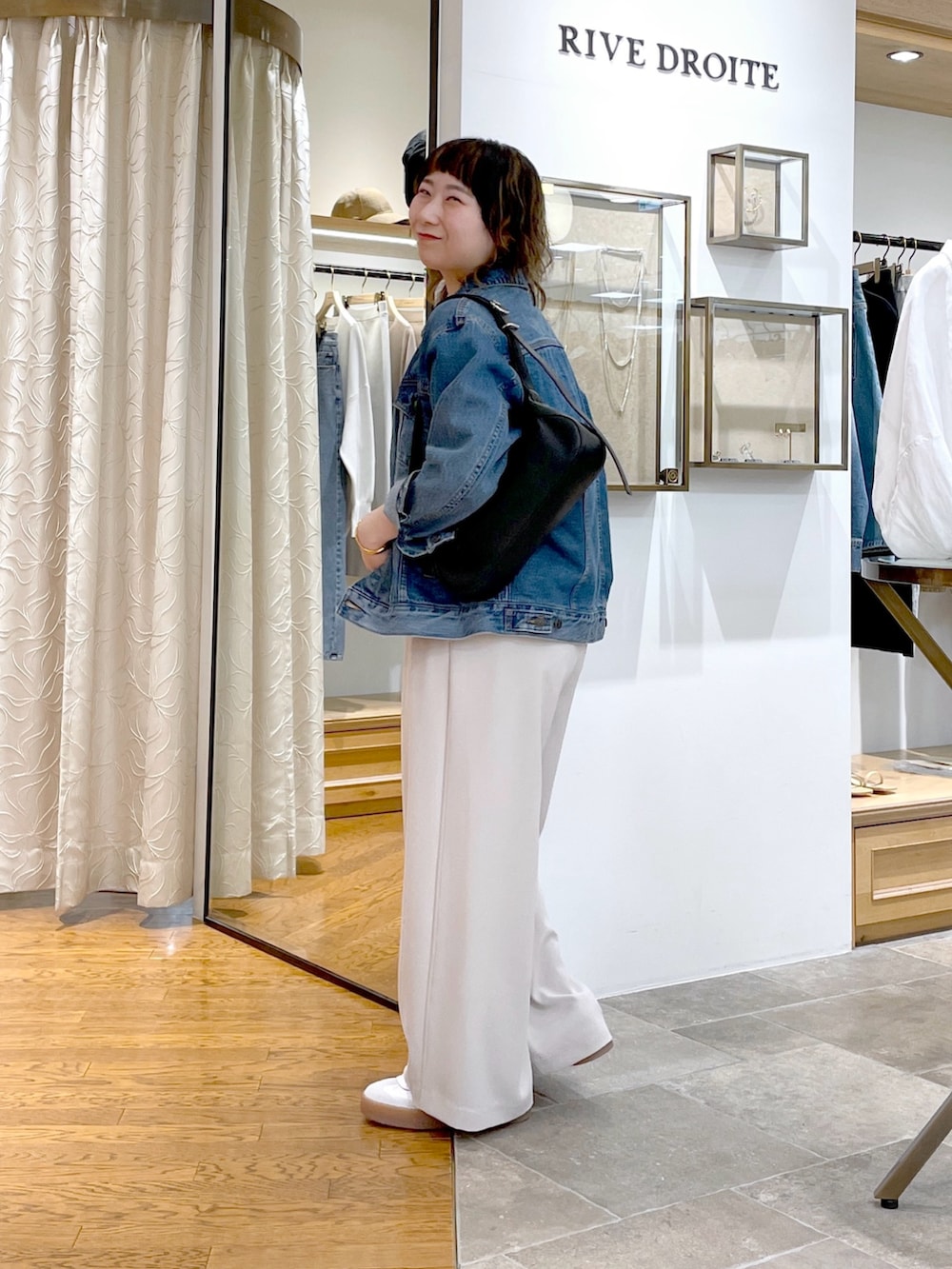ホワイト系のTシャツ/カットソー、ブラック系のハンドバッグ、ブルー系のデニムジャケットを着用したレディースの春コーディネートの2枚目の写真
