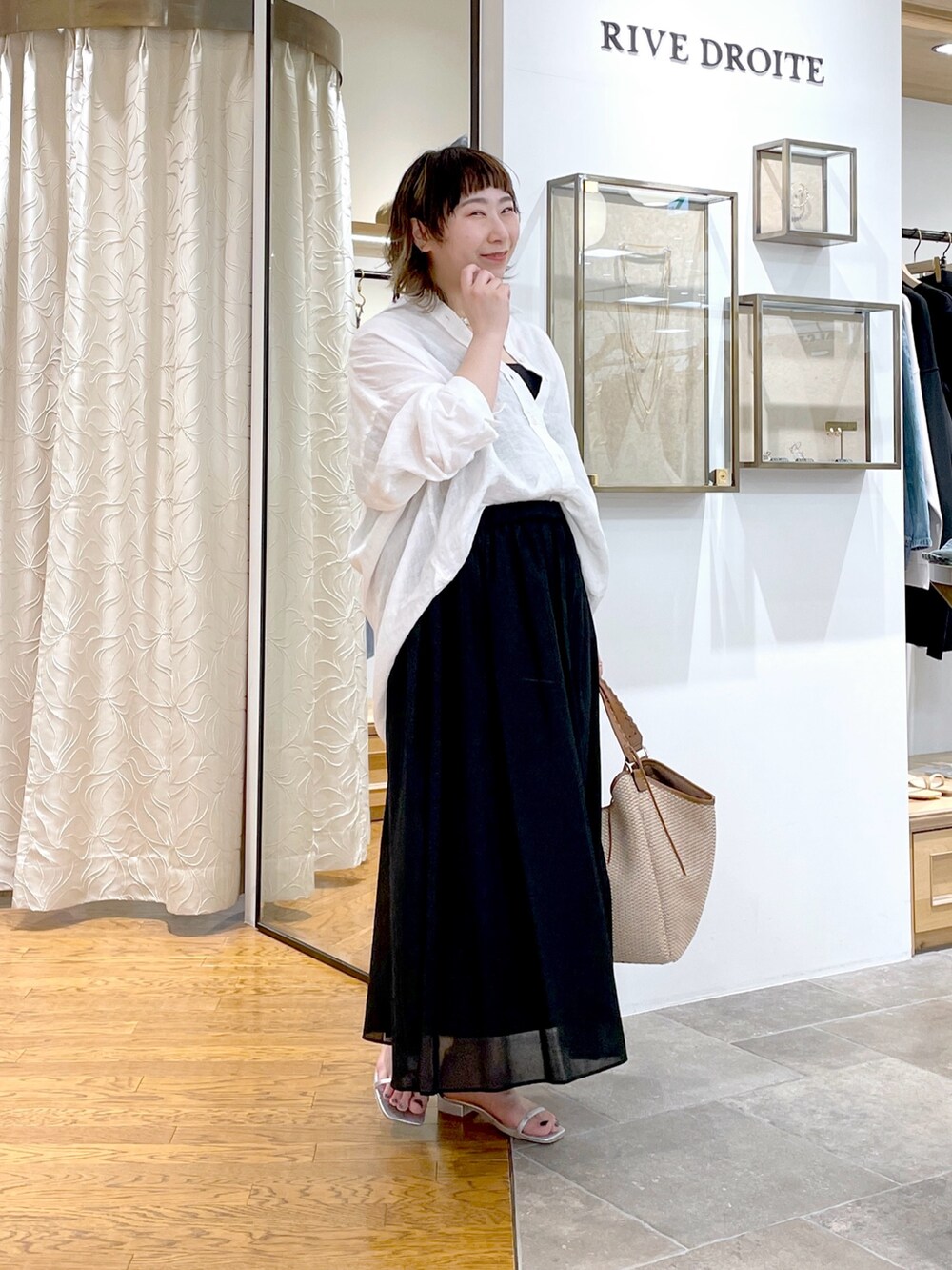 ブラック系のタンクトップ、ホワイト系のシャツ/ブラウス、ブラック系のスカートを着用したレディースの春コーディネートの2枚目の写真