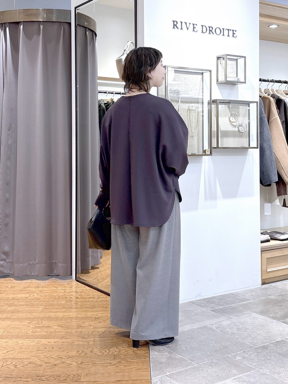 グレー系のTシャツ/カットソー、ブラック系のハンドバッグ、グレー系のスラックスを着用したレディースの秋コーディネートの2枚目の写真