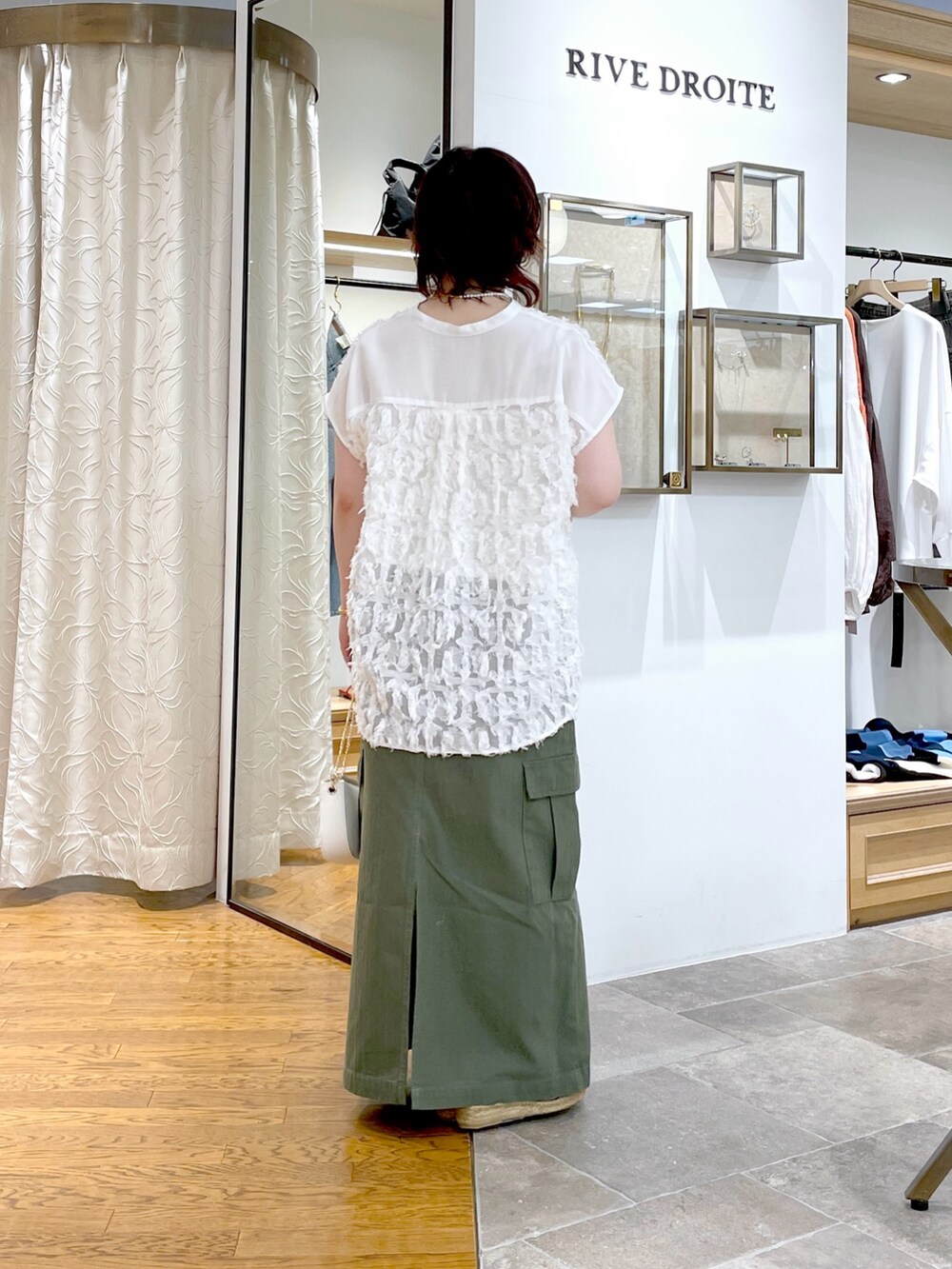 グレー系のキャミソール、ホワイト系のシャツ/ブラウス、グリーン系のスカートを着用したレディースの春コーディネートの3枚目の写真