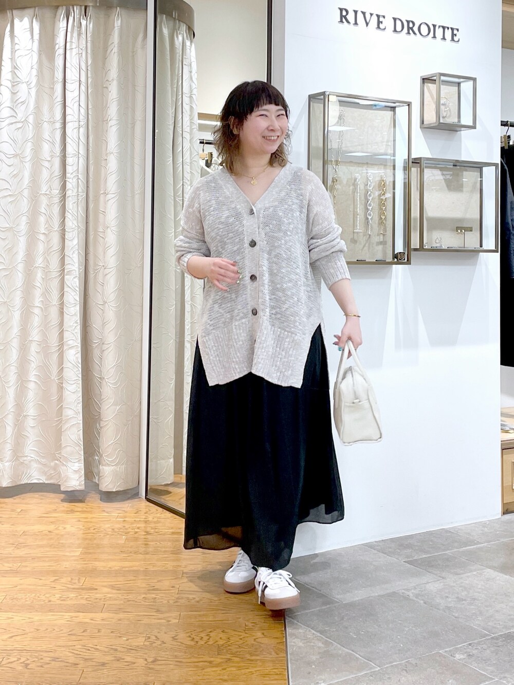 ブラック系のスカート、ホワイト系のボストンバッグ、グレー系のカーディガン/ボレロを着用したレディースの春コーディネートの5枚目の写真