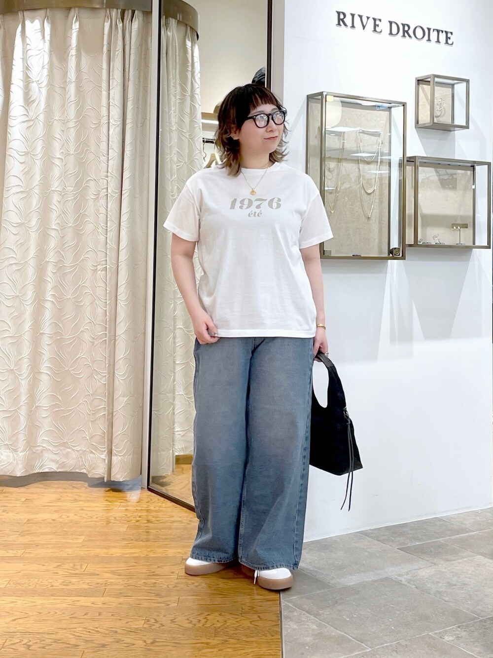 ホワイト系のTシャツ/カットソー、ブラック系のハンドバッグ、ブルー系のデニムパンツを着用したレディースの春コーディネートの2枚目の写真