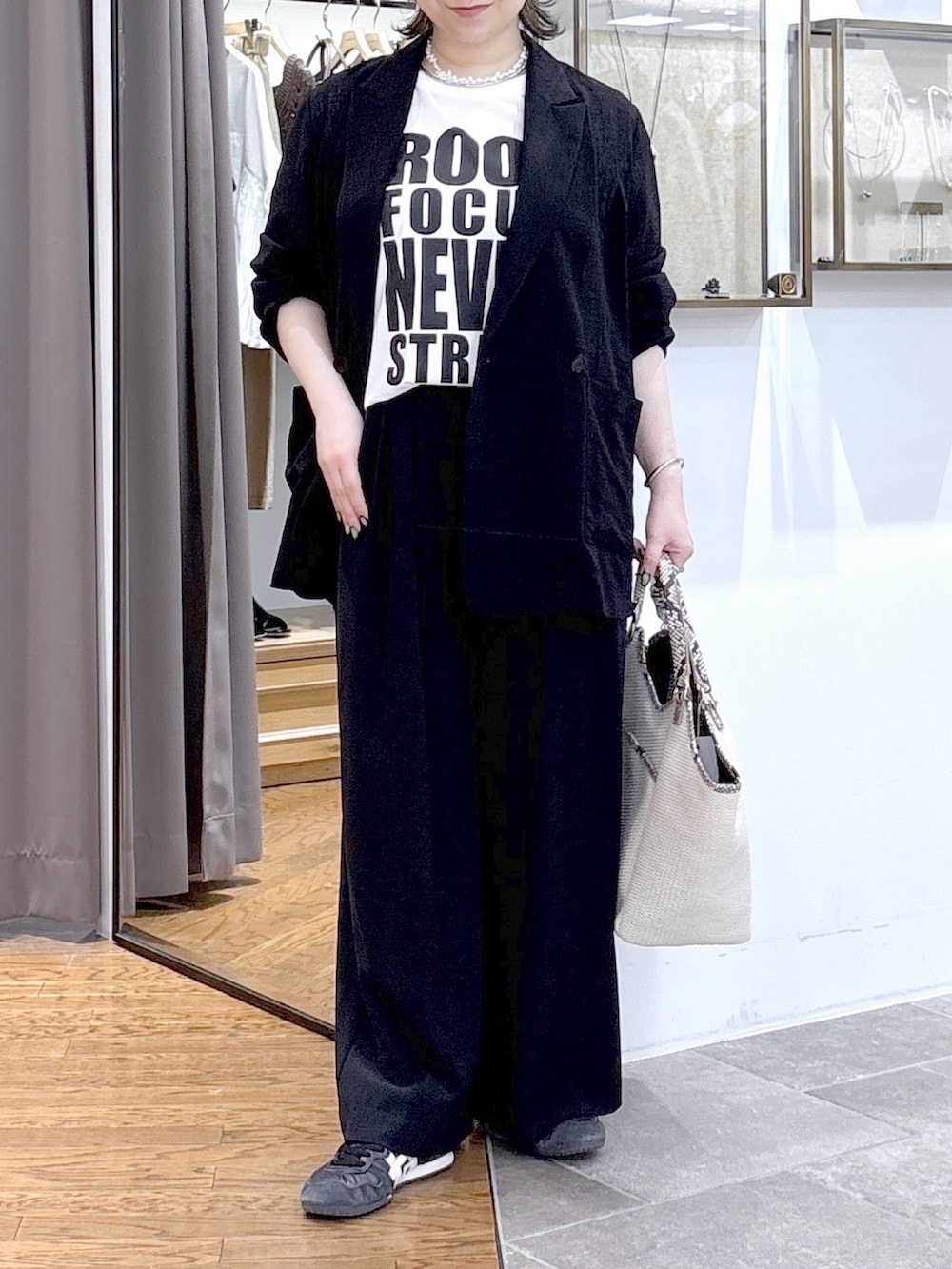 ホワイト系のTシャツ/カットソー、ブラック系のテーラードジャケット、ベージュ系のハンドバッグを着用したレディースの夏コーディネートの3枚目の写真