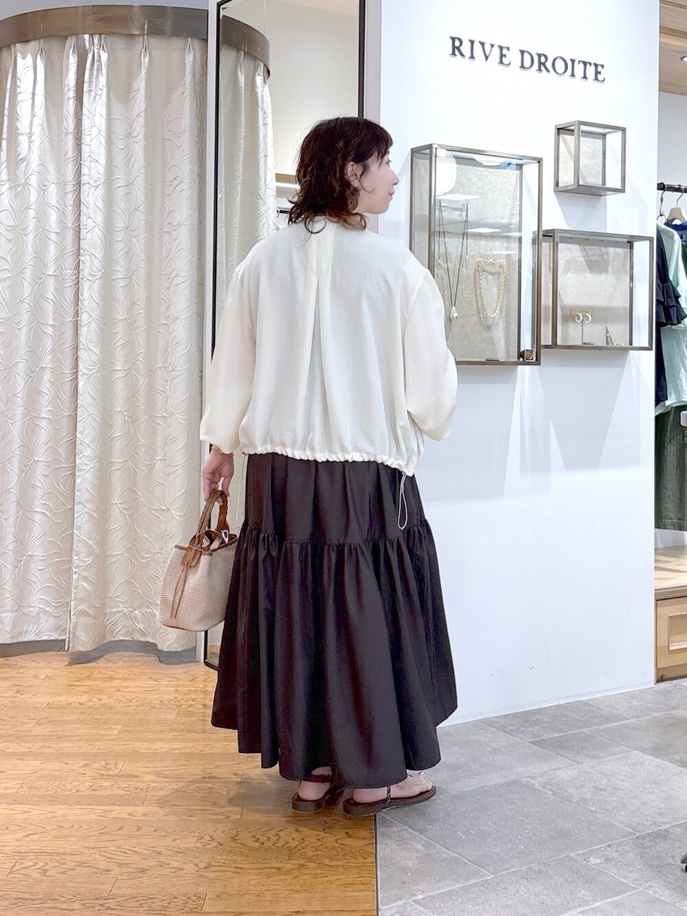 ホワイト系のブルゾン、ブラウン系のワンピース、ブラウン系のハンドバッグを着用したレディースの夏コーディネートの4枚目の写真