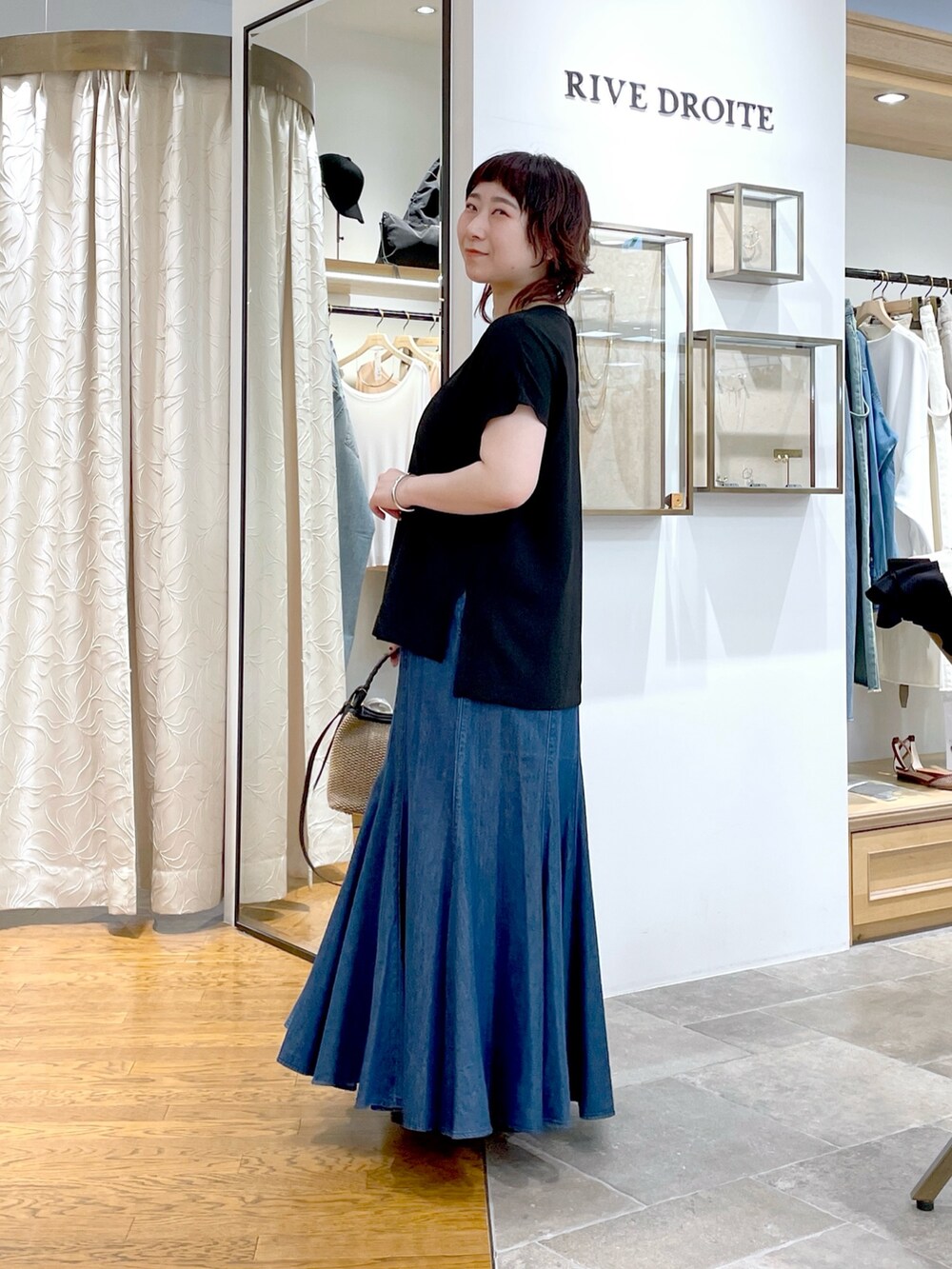 ブラック系のシャツ/ブラウス、ブルー系のスカート、ブラック系のハンドバッグを着用したレディースの春コーディネートの2枚目の写真