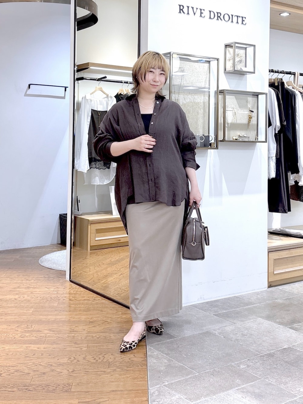 ブラック系のニット/セーター、ブラウン系のシャツ/ブラウス、ブラウン系のボストンバッグを着用したレディースの夏コーディネートの2枚目の写真
