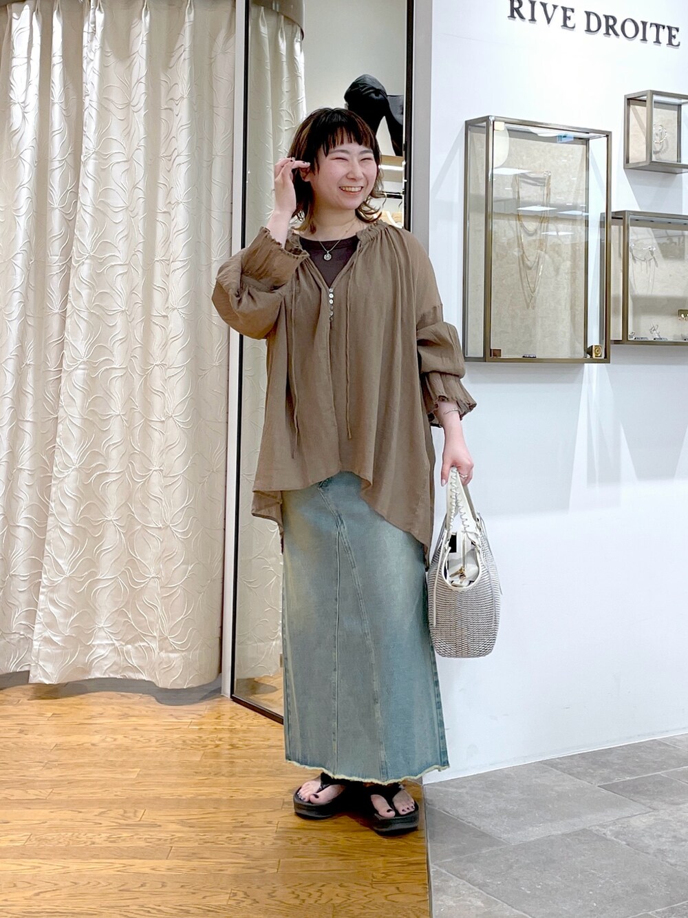 ブラウン系のキャミソール、ブラウン系のシャツ/ブラウス、ブルー系のデニムスカートを着用したレディースの春コーディネートの2枚目の写真