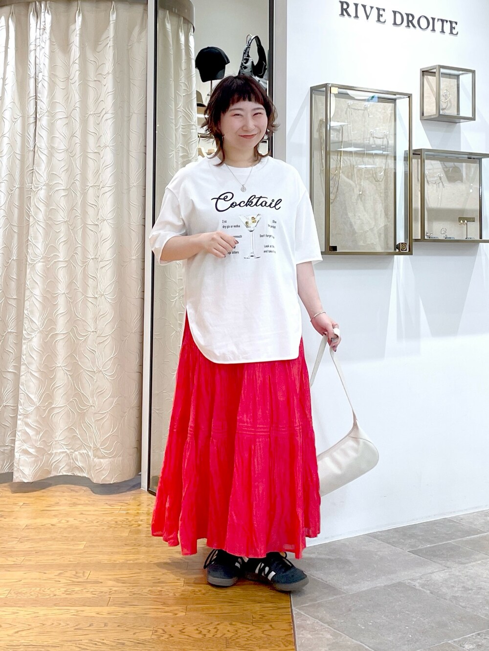 ホワイト系のハンドバッグ、ホワイト系のTシャツ/カットソー、レッド系のスカートを着用したレディースの春コーディネートの2枚目の写真