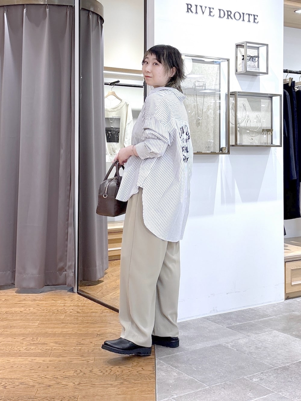 ブラウン系のボストンバッグ、イエロー系のスラックス、ホワイト系のシャツ/ブラウスを着用したレディースの春コーディネートの5枚目の写真