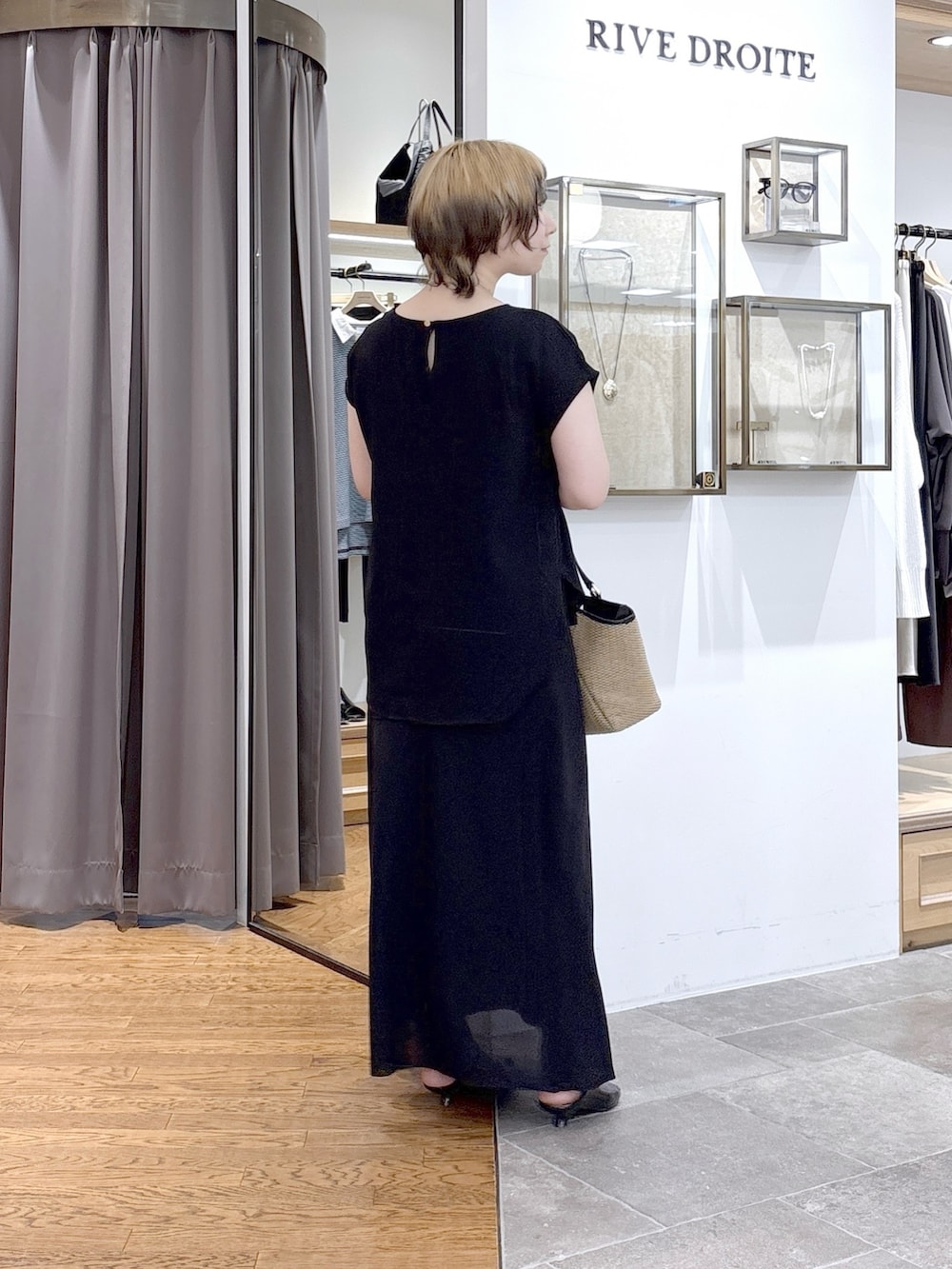 ブラック系のスカート、ブラック系のハンドバッグ、ブラック系のシャツ/ブラウスを着用したレディースの夏コーディネートの2枚目の写真
