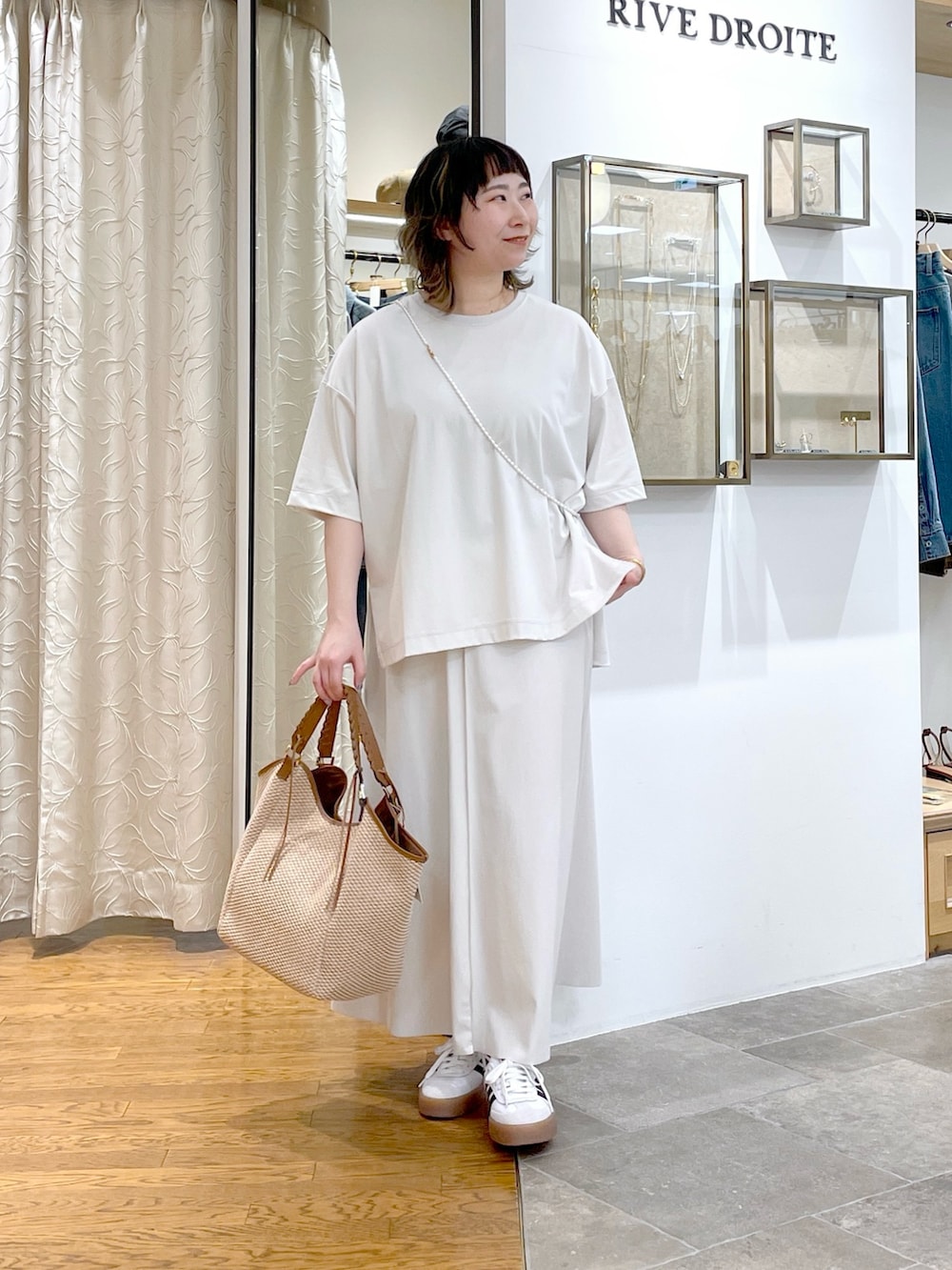 ホワイト系のTシャツ/カットソー、ブラウン系のトートバッグ、ホワイト系のスカートを着用したレディースの春コーディネートの2枚目の写真