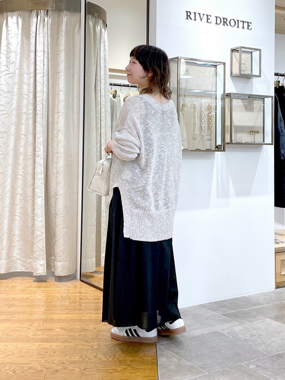 ブラック系のスカート、ホワイト系のボストンバッグ、グレー系のカーディガン/ボレロを着用したレディースの春コーディネートの6枚目の写真