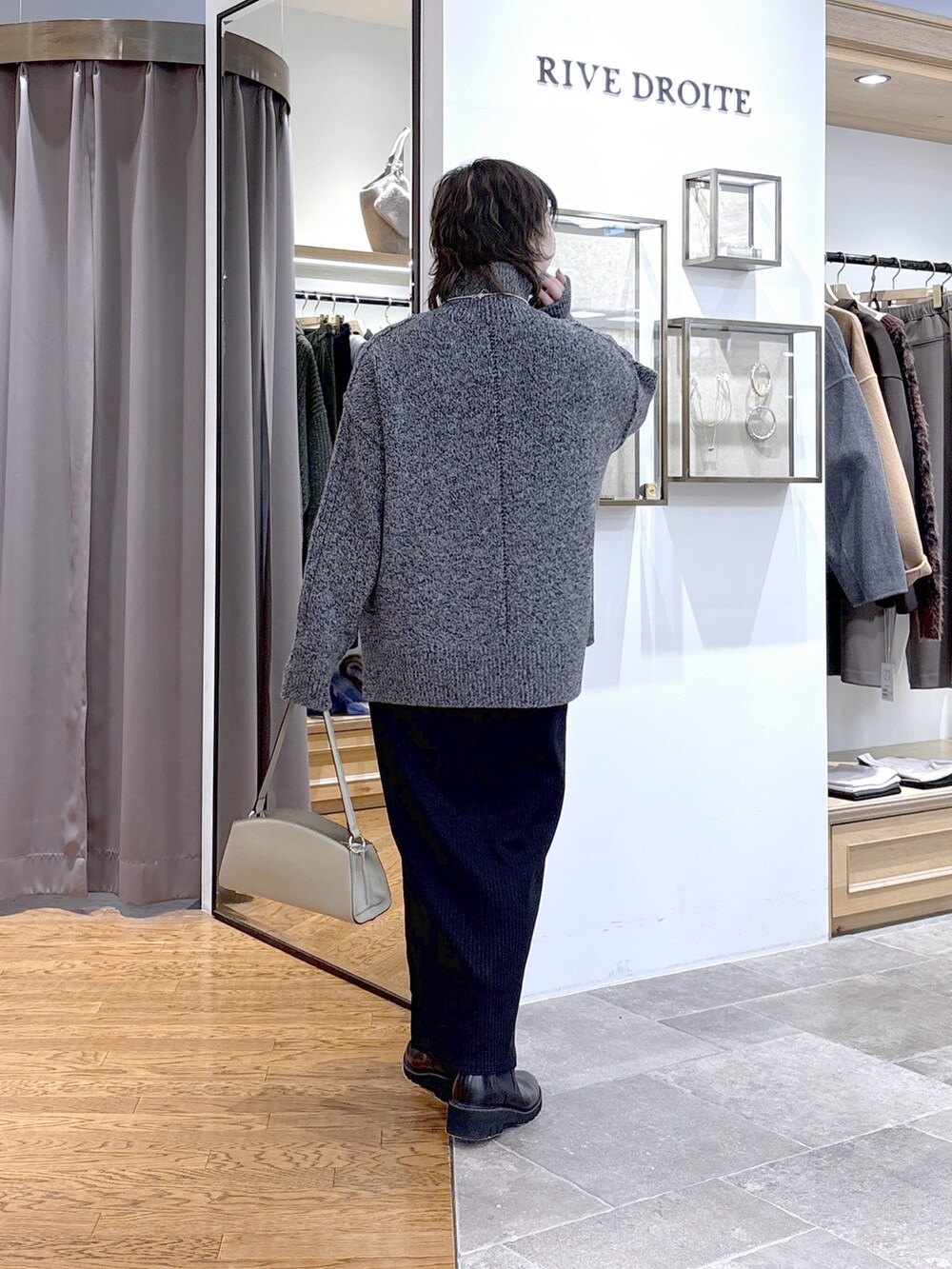 グレー系のニット/セーター、ベージュ系のハンドバッグ、ブラック系のワンピースを着用したレディースの秋コーディネートの2枚目の写真