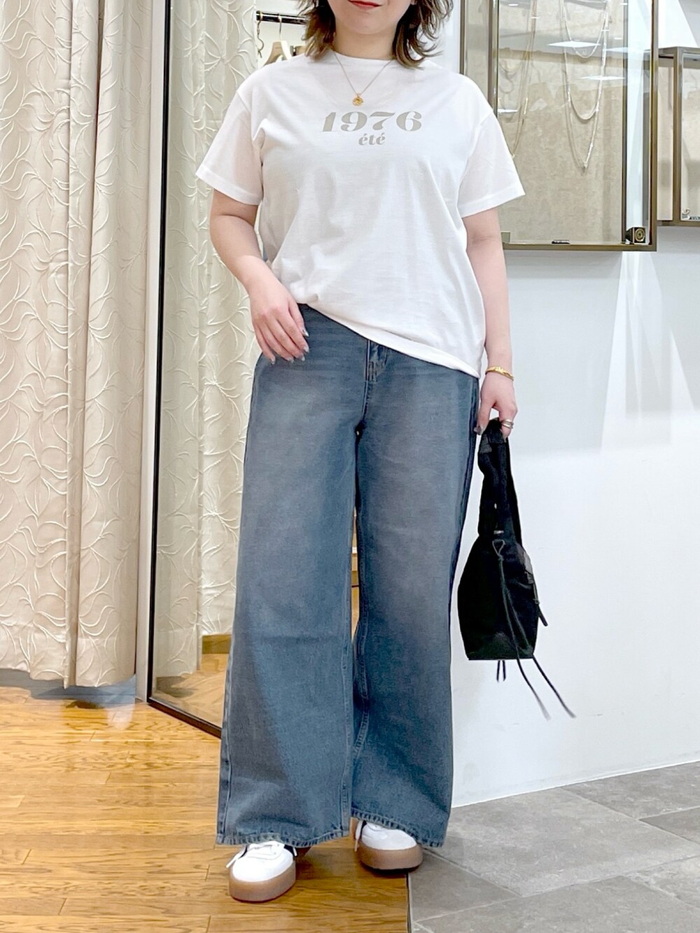 ホワイト系のTシャツ/カットソー、ブラック系のハンドバッグ、ブルー系のデニムパンツを着用したレディースの春コーディネートの5枚目の写真