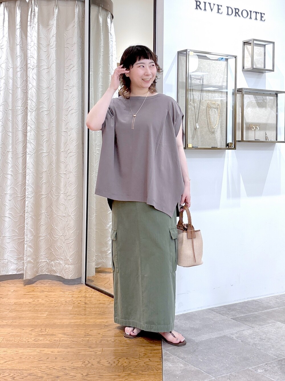 グレー系のTシャツ/カットソー、グリーン系のスカート、ブラウン系のハンドバッグを着用したレディースの夏コーディネートの2枚目の写真