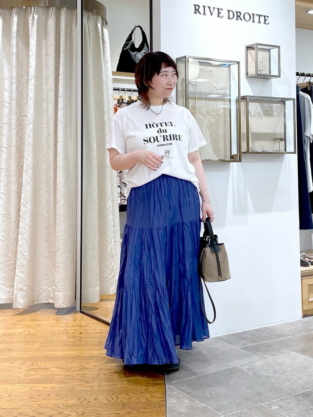 ブラック系のハンドバッグ、ブルー系のスカート、ホワイト系のTシャツ/カットソーを着用したレディースの夏コーディネートの4枚目の写真