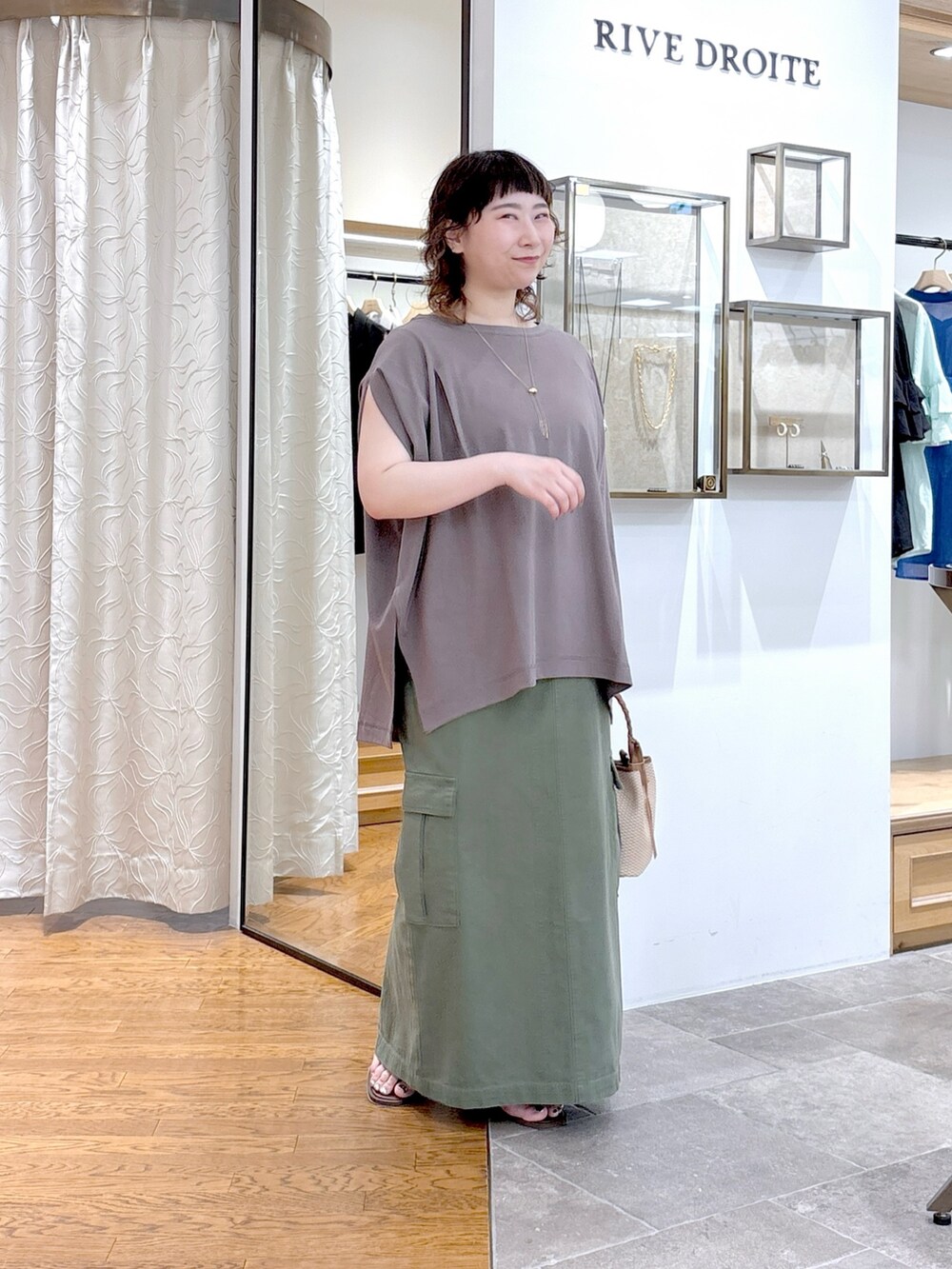 グレー系のTシャツ/カットソー、グリーン系のスカート、ブラウン系のハンドバッグを着用したレディースの夏コーディネートの4枚目の写真