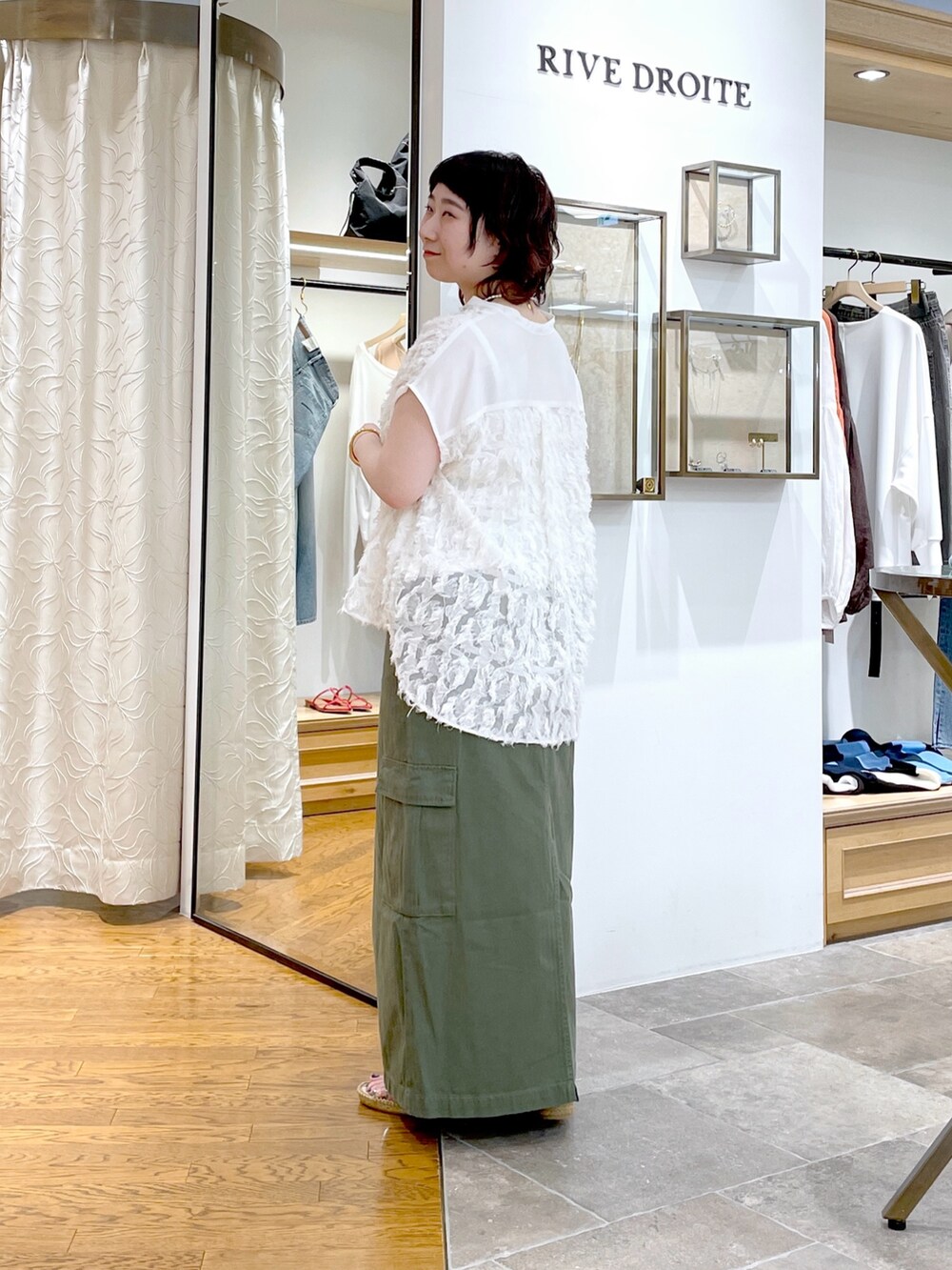 グレー系のキャミソール、ホワイト系のシャツ/ブラウス、グリーン系のスカートを着用したレディースの春コーディネートの2枚目の写真