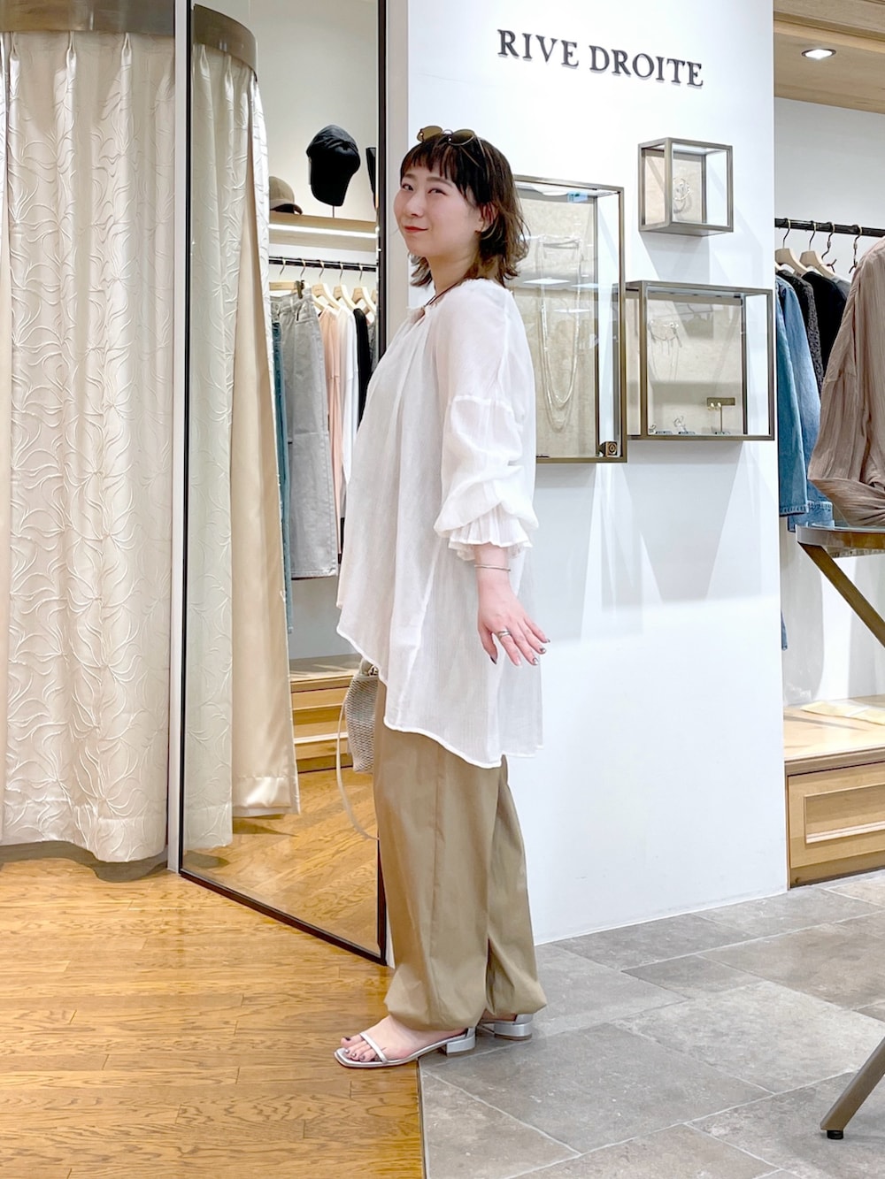 ベージュ系のタンクトップ、ホワイト系のシャツ/ブラウス、ホワイト系のハンドバッグを着用したレディースの春コーディネートの5枚目の写真