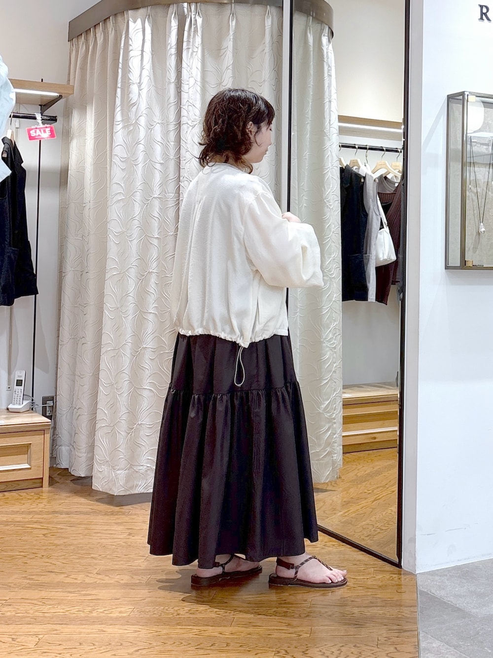 ホワイト系のブルゾン、ブラウン系のワンピース、ブラウン系のハンドバッグを着用したレディースの夏コーディネートの3枚目の写真