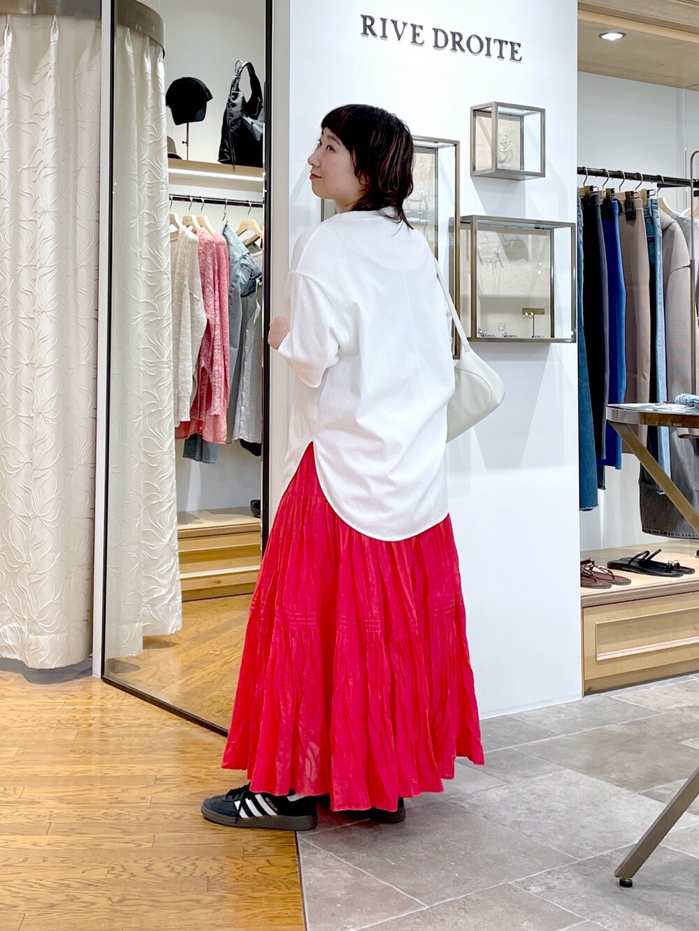 ホワイト系のハンドバッグ、ホワイト系のTシャツ/カットソー、レッド系のスカートを着用したレディースの春コーディネートの4枚目の写真