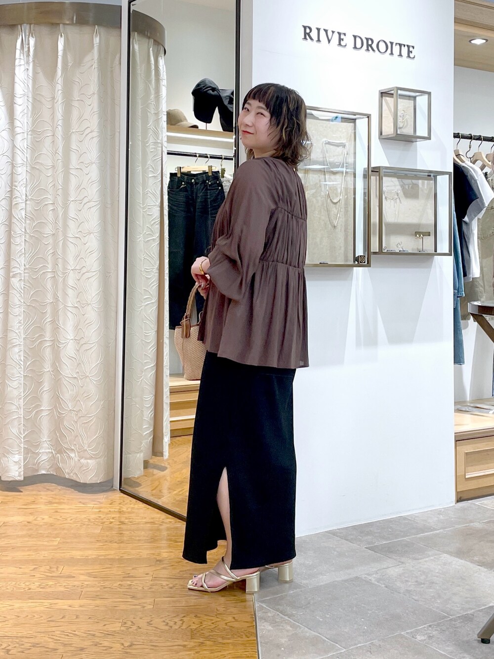 ブラウン系のシャツ/ブラウス、ブラウン系のハンドバッグ、ブラック系のワンピースを着用したレディースの春コーディネートの2枚目の写真