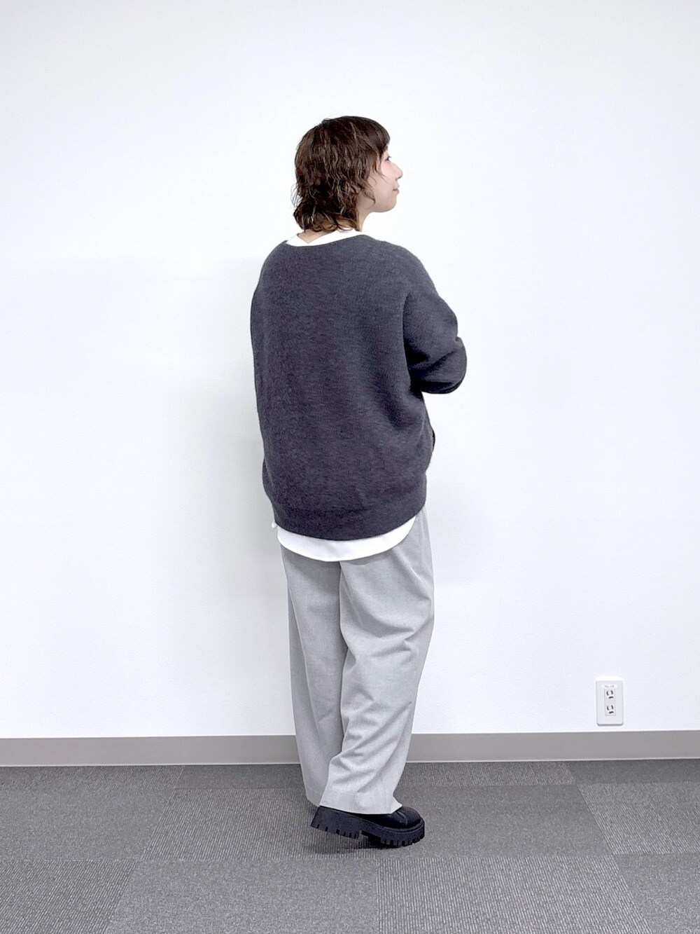 グレー系のニット/セーター、ブラック系のハンドバッグ、ホワイト系のシャツ/ブラウスを着用したレディースの秋コーディネートの2枚目の写真