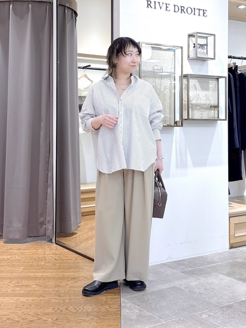 ブラウン系のボストンバッグ、イエロー系のスラックス、ホワイト系のシャツ/ブラウスを着用したレディースの春コーディネートの4枚目の写真