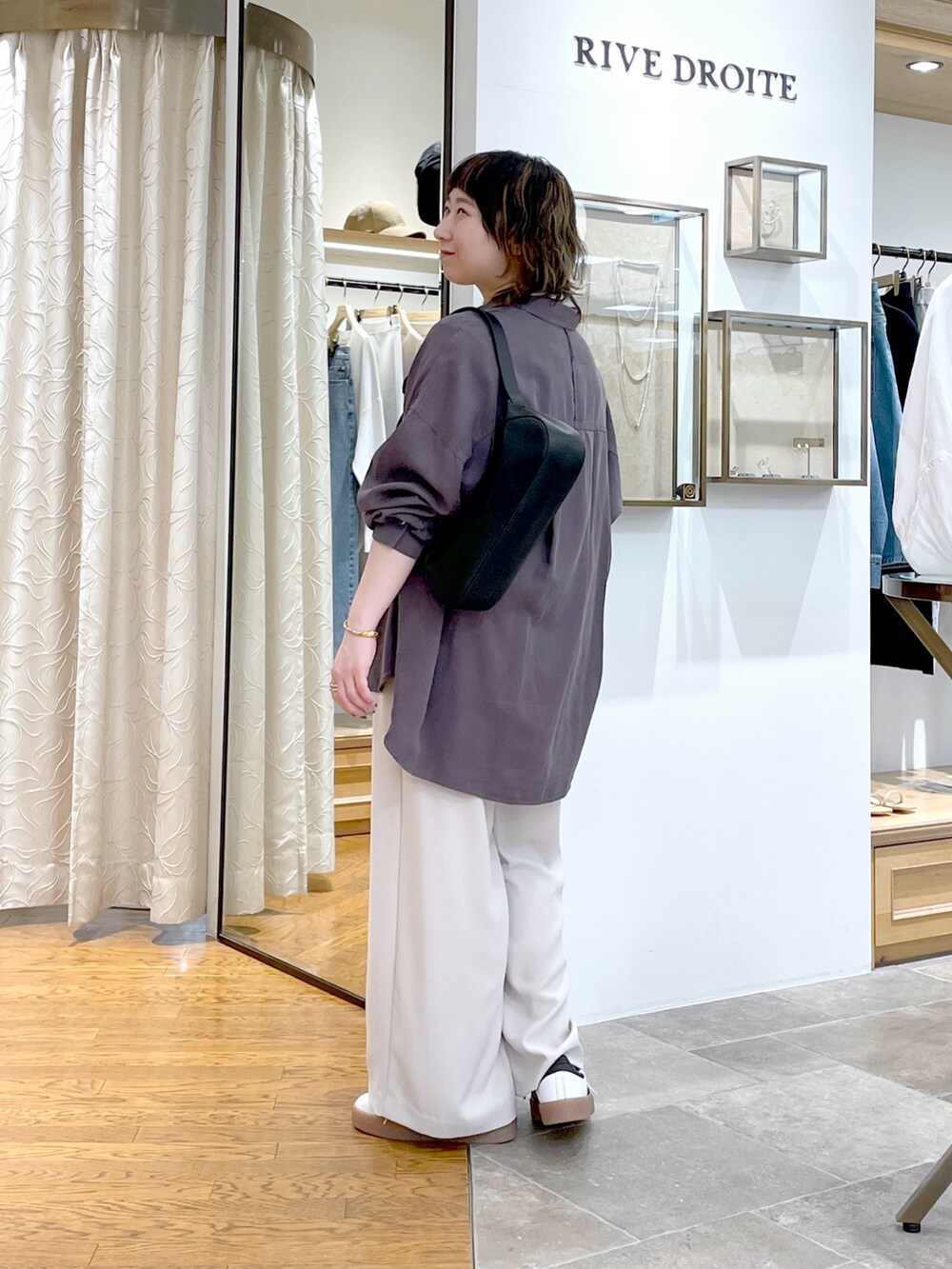 グレー系のスラックス、グレー系のシャツ/ブラウス、ホワイト系のTシャツ/カットソーを着用したレディースの春コーディネートの2枚目の写真