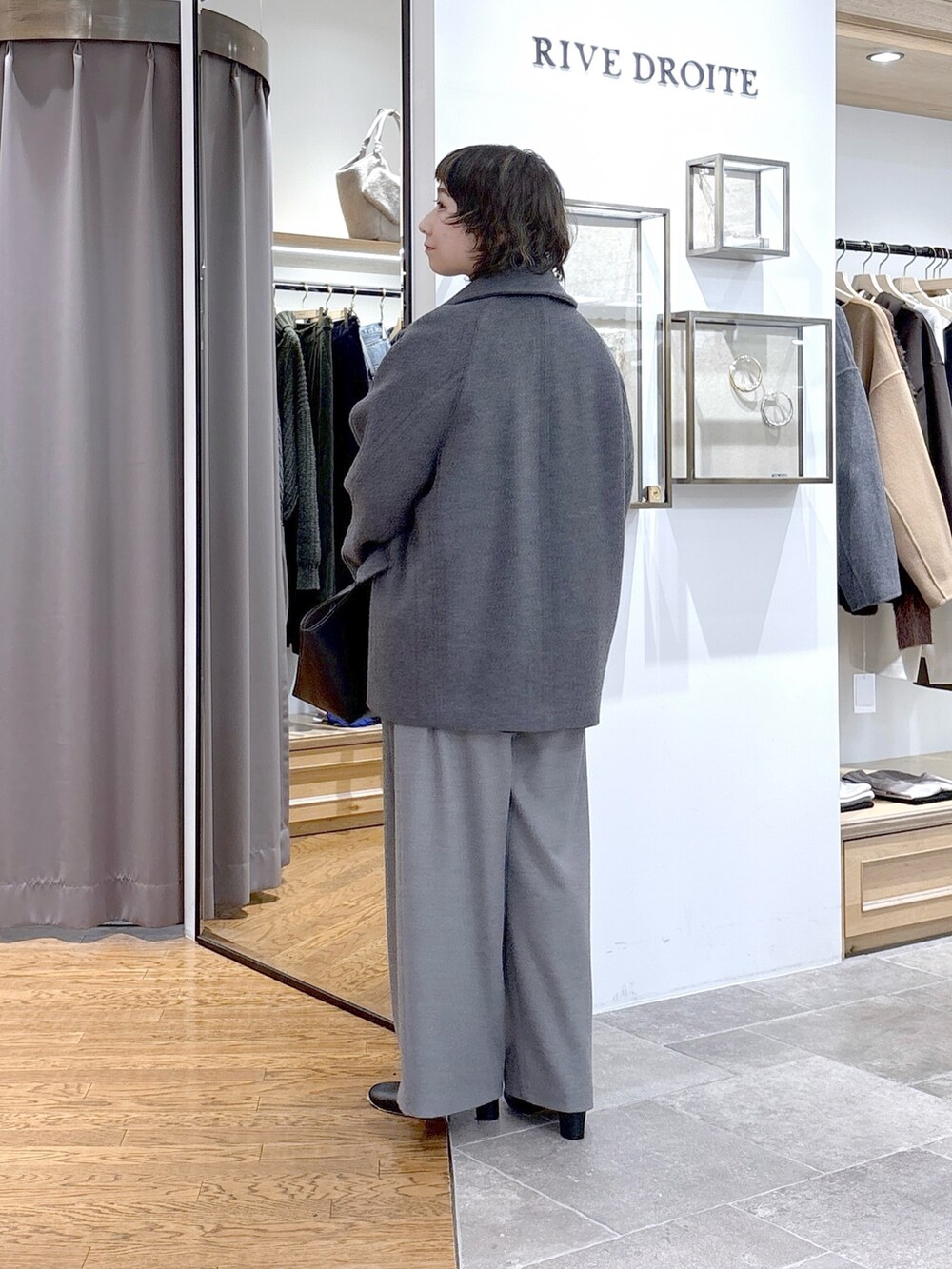 グレー系のTシャツ/カットソー、グレー系のピーコート、ブラック系のハンドバッグを着用したレディースの秋コーディネートの2枚目の写真